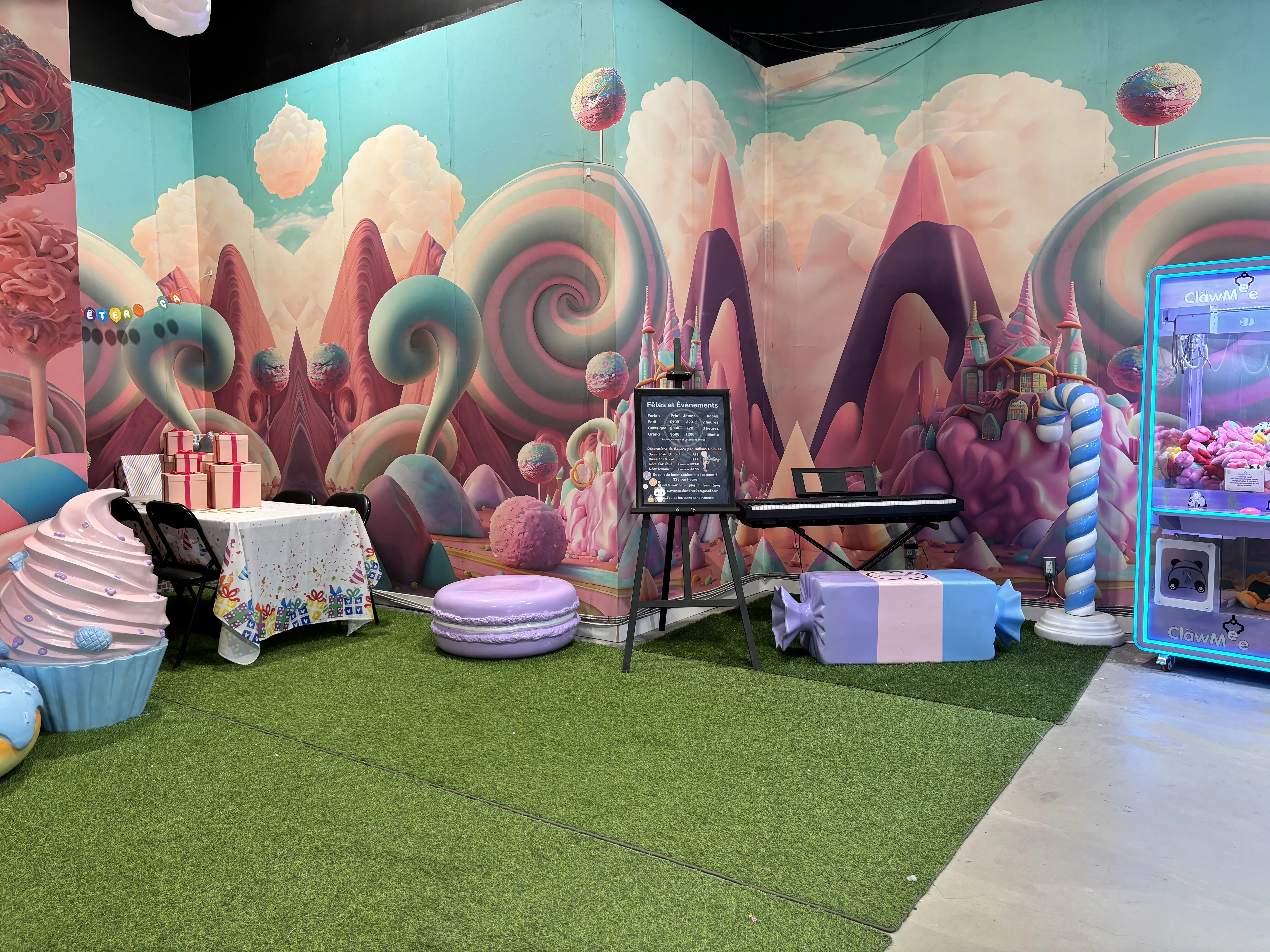 Salle de fête candyland avec machine à pince, sièges bonbon et grande murale colorée